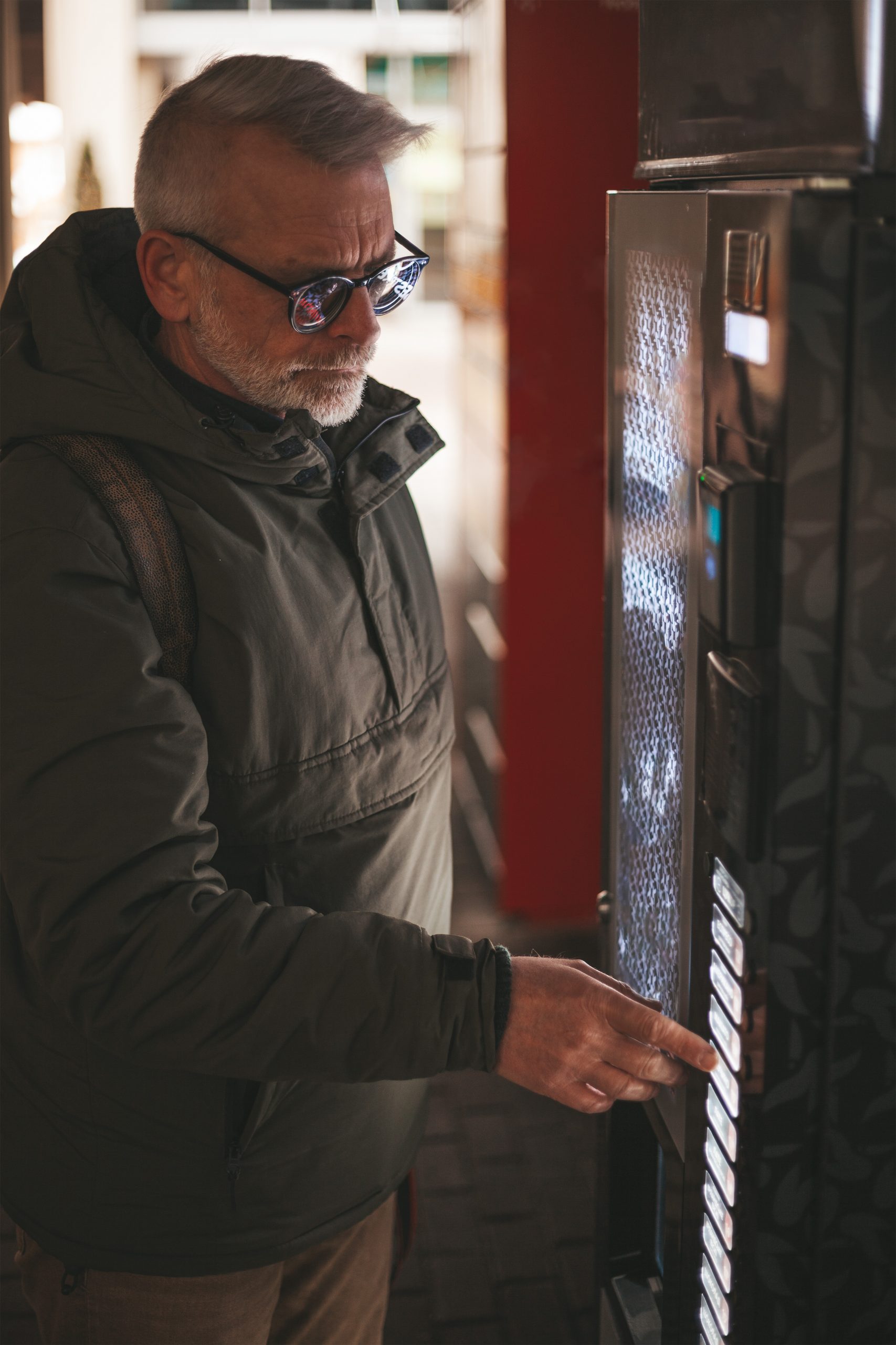 Senior man buys a drink from a vending machine. The customer mak